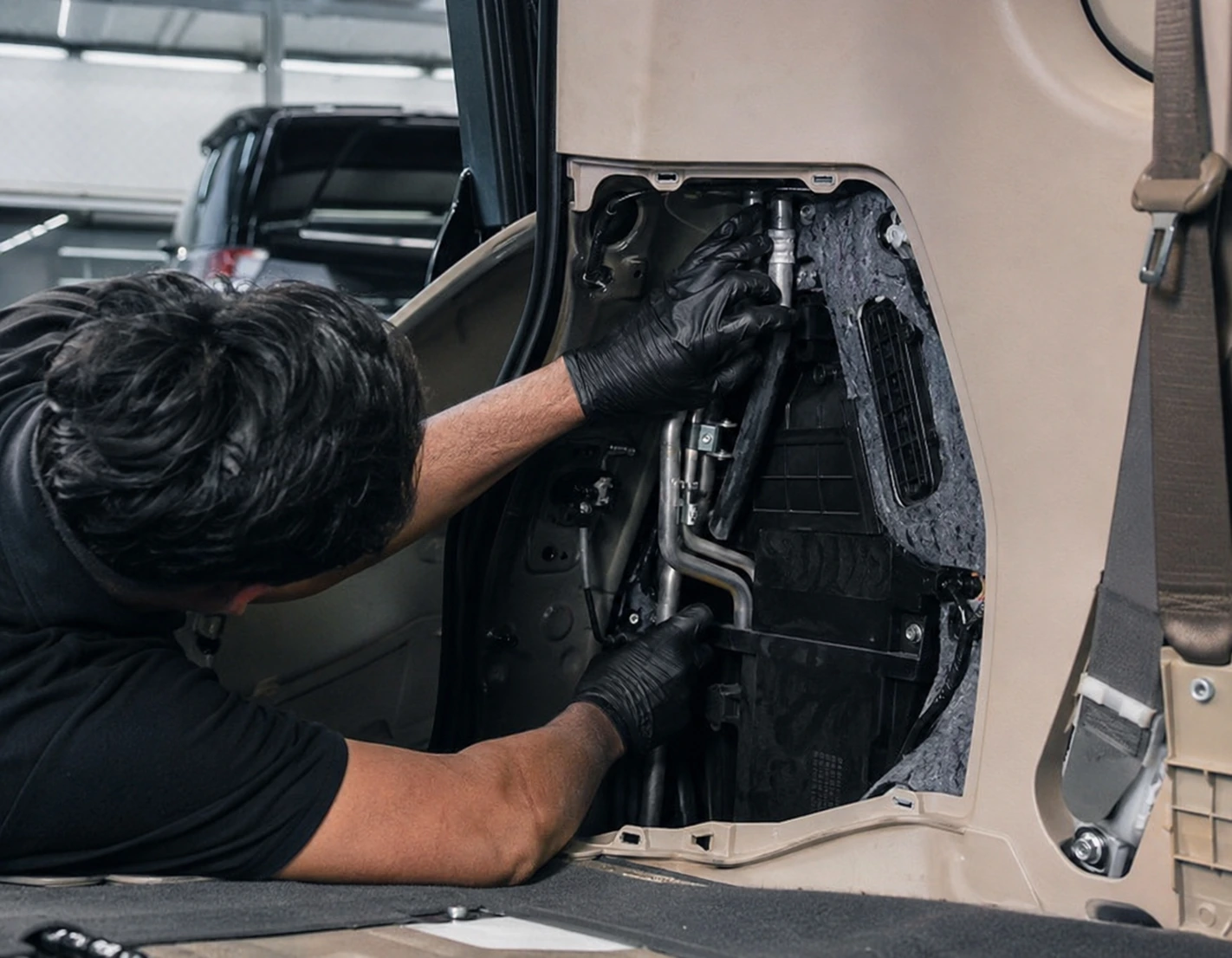 Technician inspecting rear SUV AC lines and rear HVAC components behind interior trim