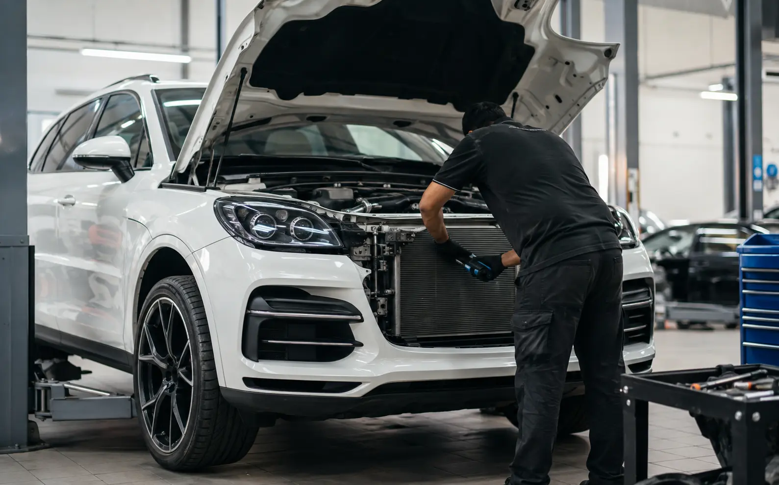 Technician inspecting AC components on a white premium SUV